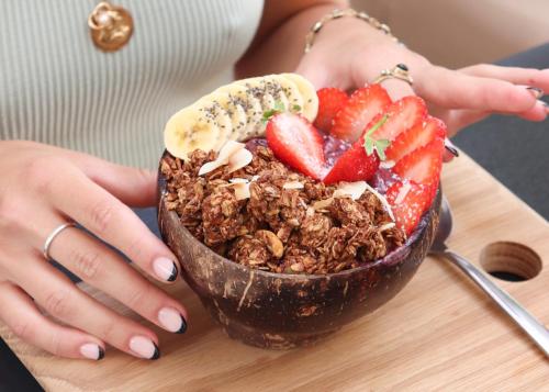 a woman holding a bowl of granola and strawberries at Neighbourgood Hill in Cape Town