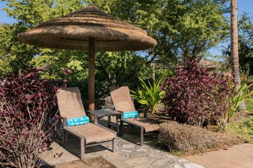 a group of chairs and an umbrella on a patio at HAWAIIANA ESCAPE Tropical 3BR Kulalani Home with Bikes and Beach Club in Waikoloa