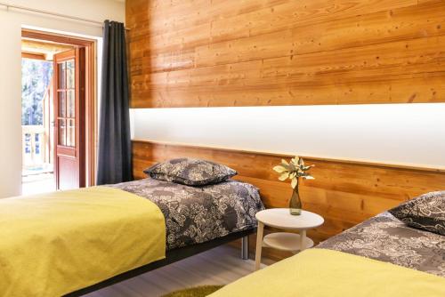 two beds in a room with wooden walls at Koivulahden Rapukartano in Mänttä