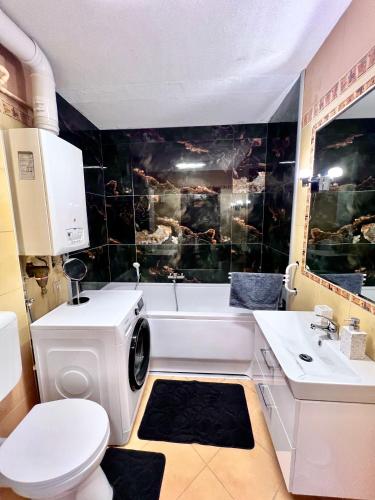 a bathroom with a white tub and a washing machine at Sunset Suites Füred in Balatonfüred