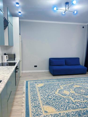 a living room with a blue couch in a kitchen at Apart Astana, Комплекс Sat City рядом с Хан-Шатыром in Astana