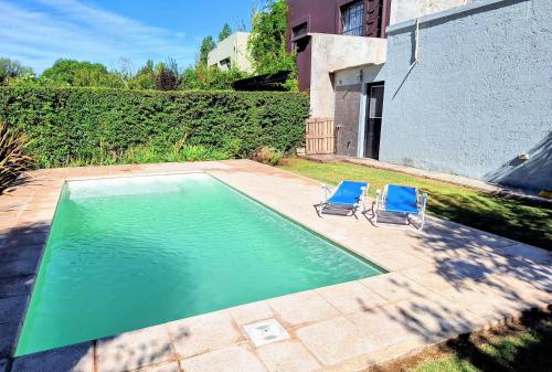 2 sillas azules sentadas junto a una piscina en SOHO Chacras de Coria Casa Completa, en Chacras de Coria