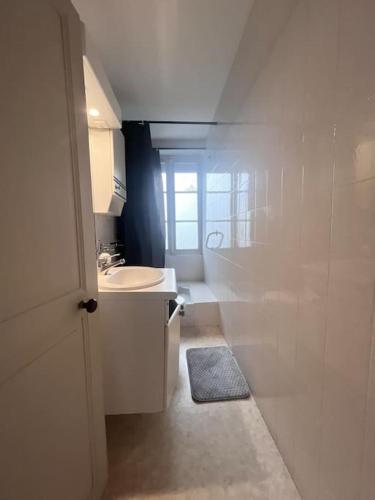 une salle de bain blanche avec un lavabo et une fenêtre dans l'établissement Town Centre with garden & free parking Le Dorat, au Dorat