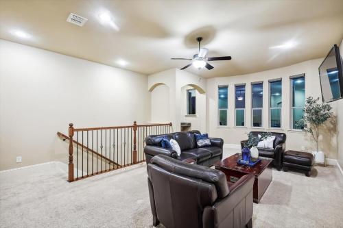 a living room with leather furniture and a ceiling fan at Lakefront Mansion with Pool and Cinema in Rowlett