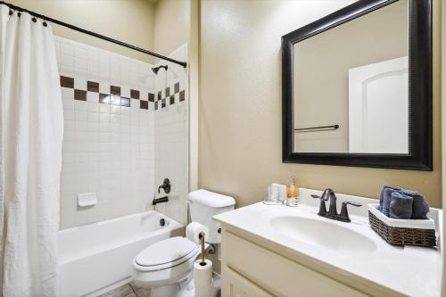 a bathroom with a sink and a toilet and a mirror at Lakefront Mansion with Pool and Cinema in Rowlett
