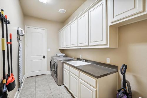 a kitchen with white cabinets and a washer and dryer at Lakefront Mansion with Pool and Cinema in Rowlett