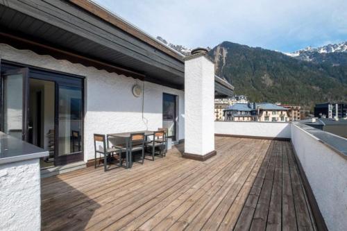 une terrasse en bois avec une table et des chaises sur une maison dans l'établissement Two bedroom apartment, Hypercenter, terrace Mont Blanc, parking, à Chamonix-Mont-Blanc