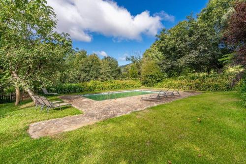a swimming pool in a yard with benches around it at Casa de Ansemondes in Refoios do Lima