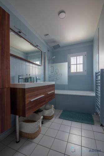 une salle de bain avec un lavabo, une baignoire et un miroir dans l'établissement Maison rénovée proche mer, à Pornic