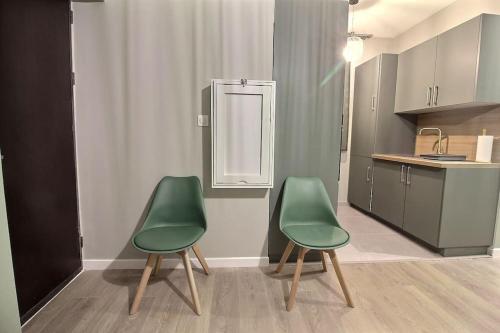 - deux chaises vertes dans la cuisine équipée d'un réfrigérateur dans l'établissement L'Auberge d'Auber, à Aubervilliers