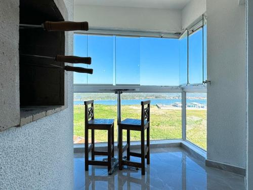 a table with two chairs in front of a window at Resid. Clube Mar Grosso - Laguna - LAG801 in Laguna