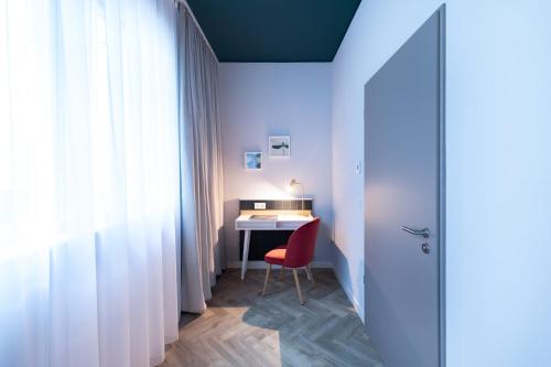 a small room with a desk and a red chair at Holiday Inn - the niu, Flower Konstanz by IHG in Konstanz