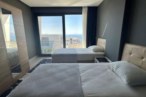 two beds in a room with a large window at Villa RADA in Bogazici