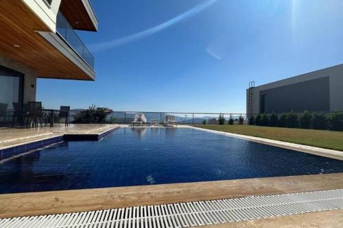a swimming pool in front of a building with the ocean at Villa RADA in Bogazici