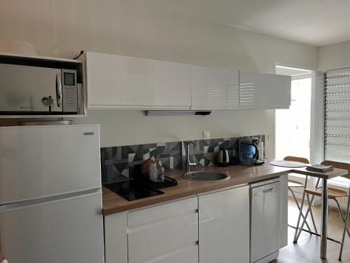 une cuisine blanche avec un évier et un micro-ondes dans l'établissement Centre Reims Cathédrale avec balcon, à Reims