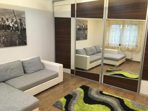 a living room with a couch and mirrors at Rabbit apartman in Mosonmagyaróvár