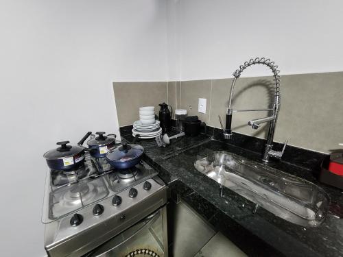 a kitchen counter with a stove and a sink at Suíte3 Privativa Climatizada Mobiliada com Garagem e Wi-Fi in Goiânia