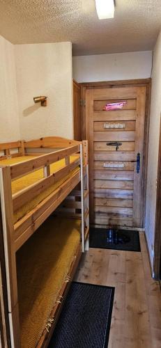 Cette chambre dispose de lits superposés et d'une porte en bois. dans l'établissement Résidence Les Arolles - Studio cabine 4 personnes 2 exposé Sud MAE-7081, à Valloire