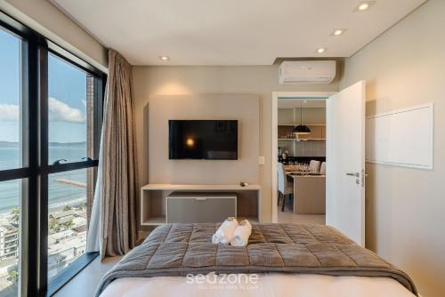 a bedroom with a bed and a large window at MHF II - Apts Variados em Prédio com Vista para o Mar em Itapema in Itapema