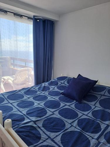 a blue and white bed in a room at Reñaca Gran terraza con vista al mar in Viña del Mar