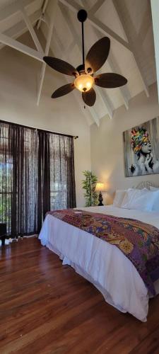 Caye Caulker Boutique Guesthouse 7 في كاي كولكر: غرفة نوم بها سرير ومروحة سقف