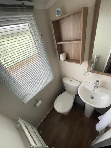 a bathroom with a toilet and a sink at Lake District Stunning Lodge in Plumbland