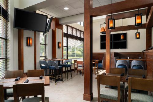 a restaurant with tables and chairs and a flat screen tv at DoubleTree by Hilton Bradley International Airport in Windsor Locks