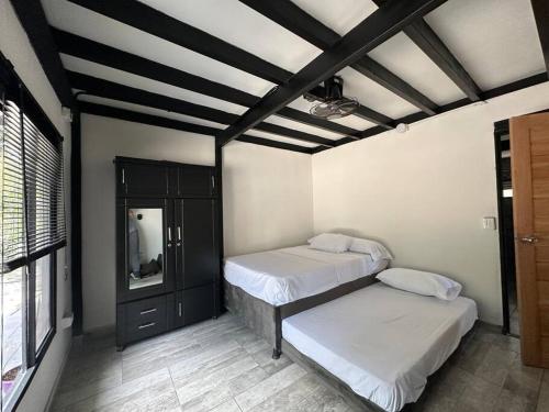 a bedroom with two beds and a ceiling with beams at Moderna casa campestre in Guamo