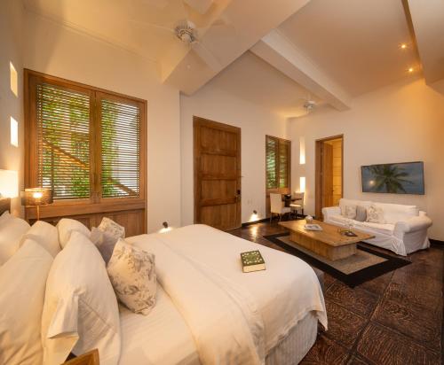 une chambre avec un grand lit blanc et un canapé dans l'établissement Casa Belle Cartagena Hotel Boutique, à Carthagène des Indes