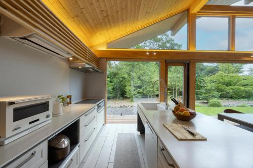 a kitchen with white cabinets and a large window at Villa Metsä KARUIZAWA ヴィラメッサ軽井沢 in Karuizawa