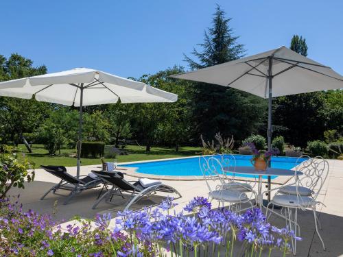 two umbrellas and a table and chairs next to a pool at Le Boisdalon in Yviers