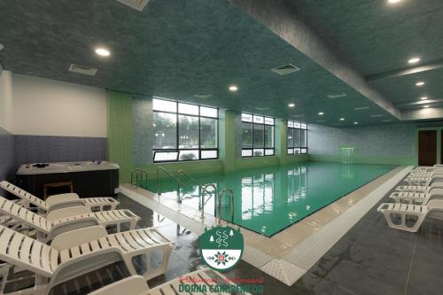a swimming pool with white chairs in a building at Casa Sofia Dorna Candrenilor in Dorna Cîndrenilor
