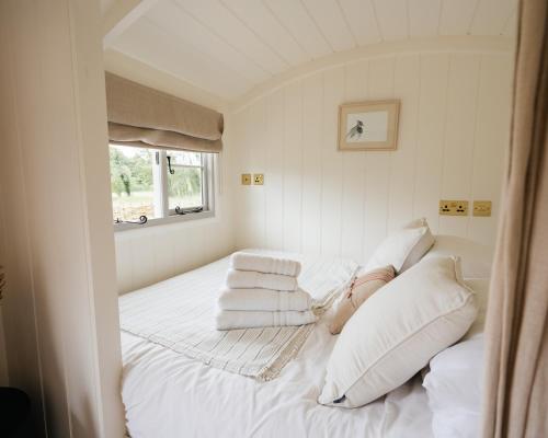 a bedroom with two beds with white pillows and a window at Lapwing Hut in Cholderton