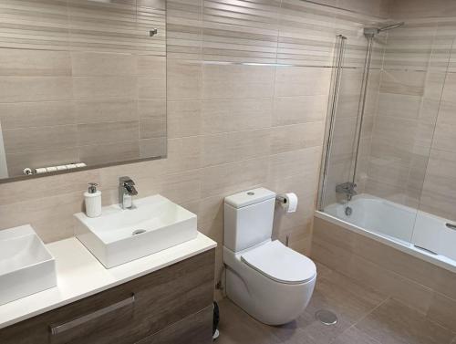 a bathroom with a toilet and a sink and a tub at Aribela in Badajoz