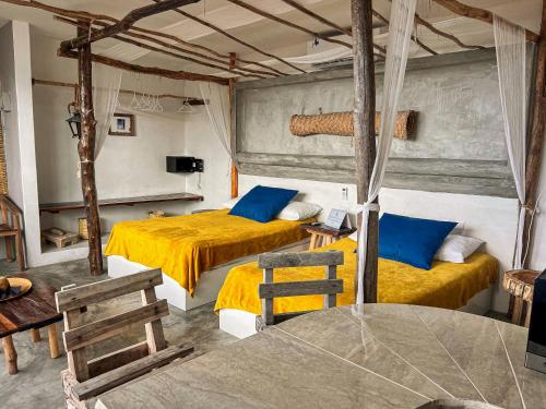 a bedroom with two beds with yellow sheets and blue pillows at Departamentos Maya in Isla Mujeres