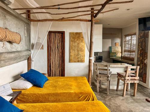 a bedroom with a bed with yellow sheets and a table at Departamentos Maya in Isla Mujeres