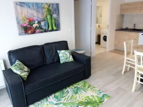 a black couch in a living room with a kitchen at la Besotte 2 pièces 40 m2 in Esbly