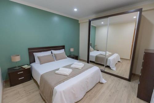 ein Schlafzimmer mit einem großen Bett und einem Spiegel in der Unterkunft Casa da Vila in Ribeira de Pena