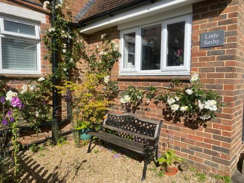 a bench in front of a brick house with flowers at Little Saxby in Crowborough