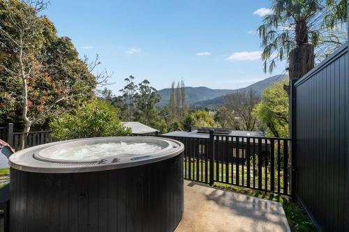 a hot tub outside of a fence with mountains in the background at Station Penthouse with Private Spa in Warburton