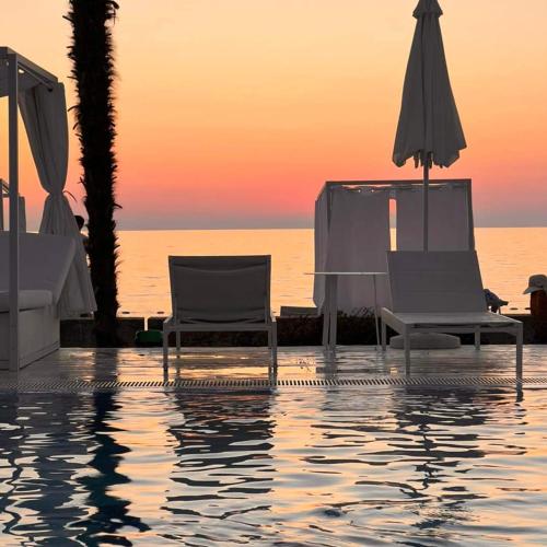 two chairs and an umbrella next to a swimming pool at Dreamlend oasis chakvi Apartament in Chakvi