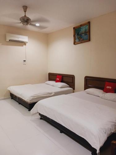 two beds in a room with red pillows on them at Hotel Kavanass Inn in Simpang