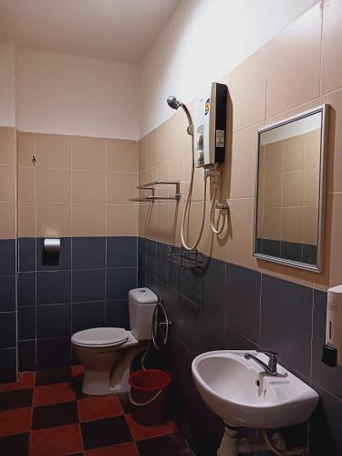 a bathroom with a sink and a toilet and a mirror at Hotel Kavanass Inn in Simpang
