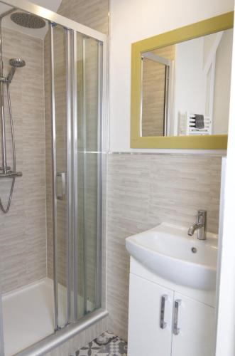 a bathroom with a shower and a sink and a mirror at Le Gîte des Violettes in Ger