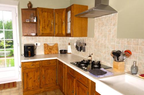 a kitchen with wooden cabinets and a stove top oven at Le Gîte des Violettes in Ger