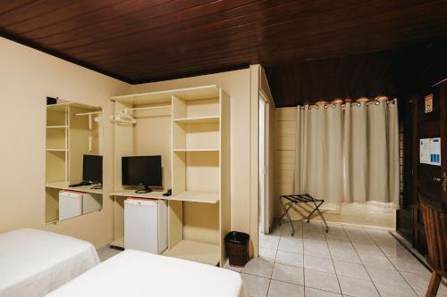 a bedroom with two beds and a desk with a television at Pousada Lenda das Águas in Fernando de Noronha