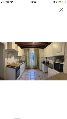 une cuisine avec des armoires blanches et un sol carrelé dans l'établissement Maison 5 mn gare sncf, à Bourges