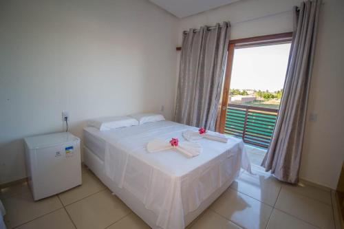 a bedroom with a bed with white sheets and a window at Villa Coco Beach Preá in Prea
