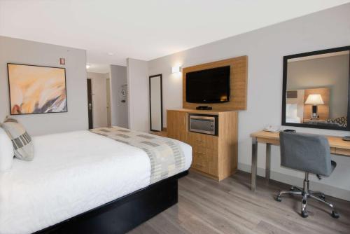 a hotel room with a bed and a desk and a television at Coast Abbotsford Hotel & Suites in Abbotsford