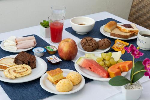 a table with plates of breakfast food on it at Hotel Ilhabela in Ilhabela